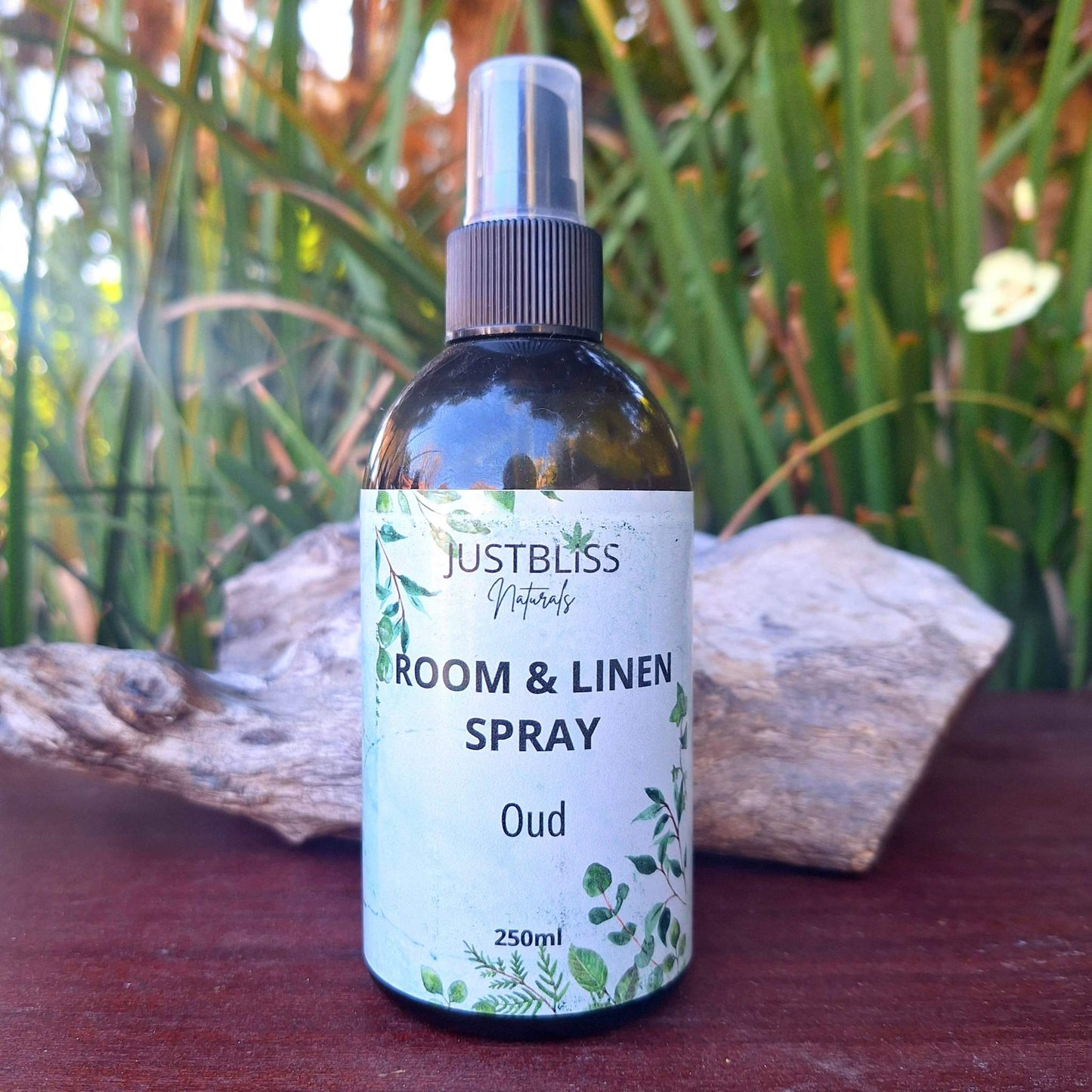 ROOM & LINEN SPRAY bottle labeled "Oud" with greenery background.