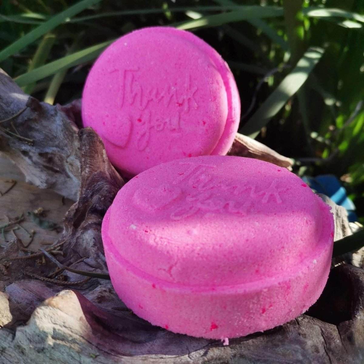 Pink "Thank You" bath bomb on natural wood background, ideal for moisturizing and softening skin, vegan and cruelty-free, bubblegum scent.