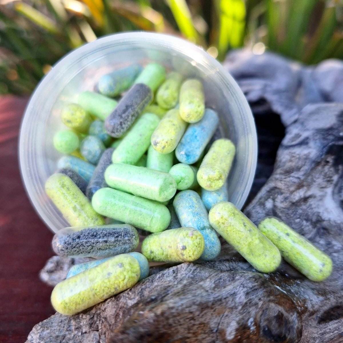 Colorful Bath Chill Pillz capsules spilling from container on wood surface.