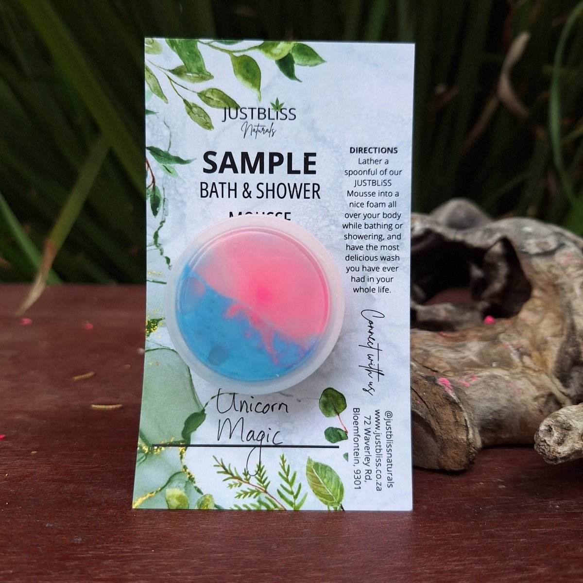 Sample size of JUSTBLiSS Unicorn Magic bath and shower mousse in a 10ml container, shown on a wooden surface with greenery background.