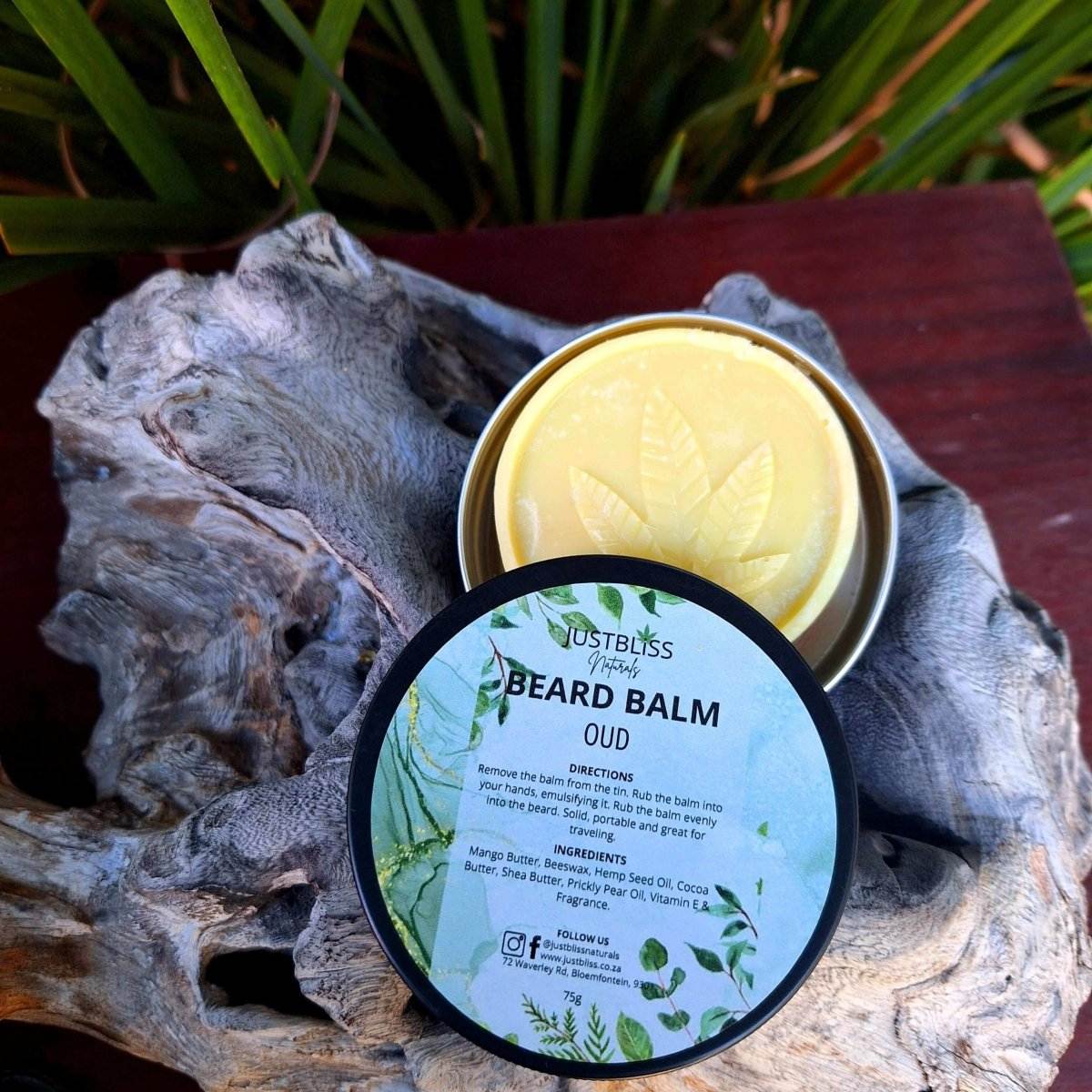 BEARD BALM Oud with lid off, revealing yellow balm, placed on textured surface.