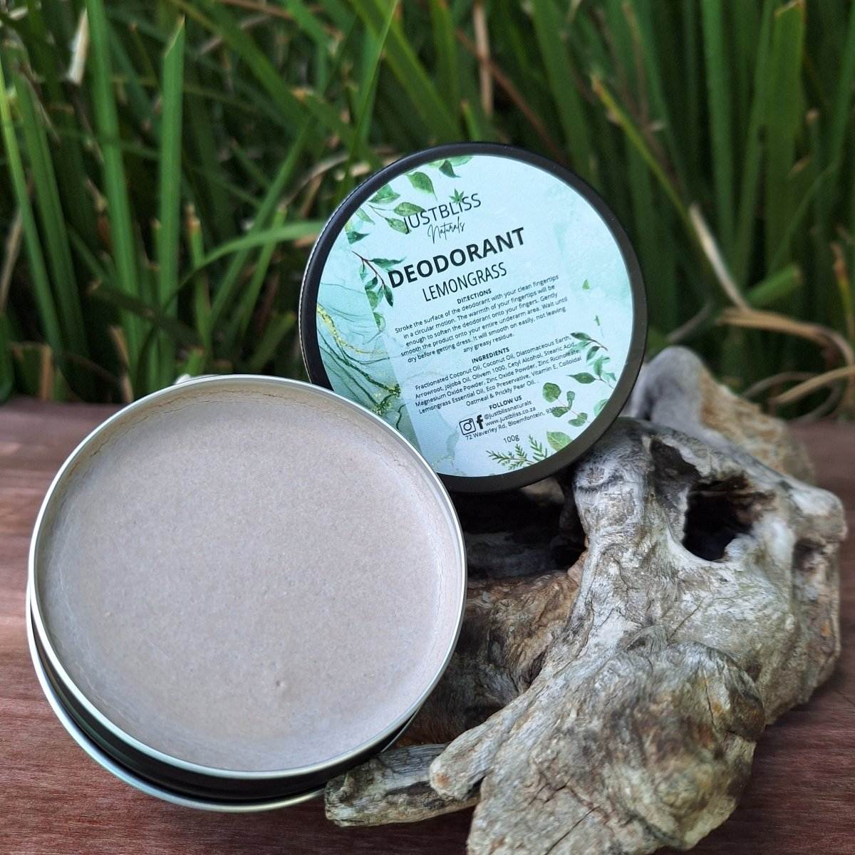 Natural lemongrass deodorant in an open tin, showcasing creamy texture with plant background.