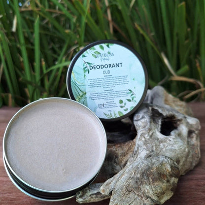 Natural JUSTBLiSS Oud Deodorant in open tin on wooden surface with greenery.