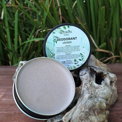 Natural lavender deodorant in open tin on rustic wood, surrounded by greenery.