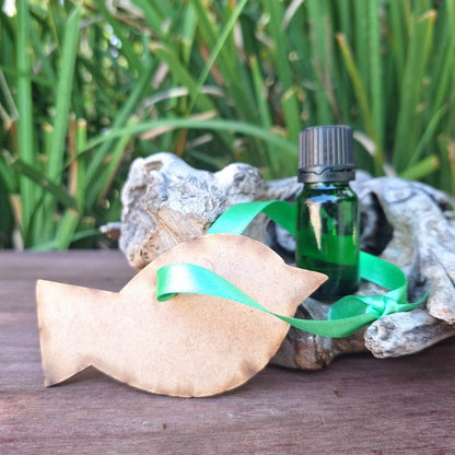 Wooden Hanging Diffuser with mystery scent and green fragrance oil bottle on rustic wooden surface against leafy background.