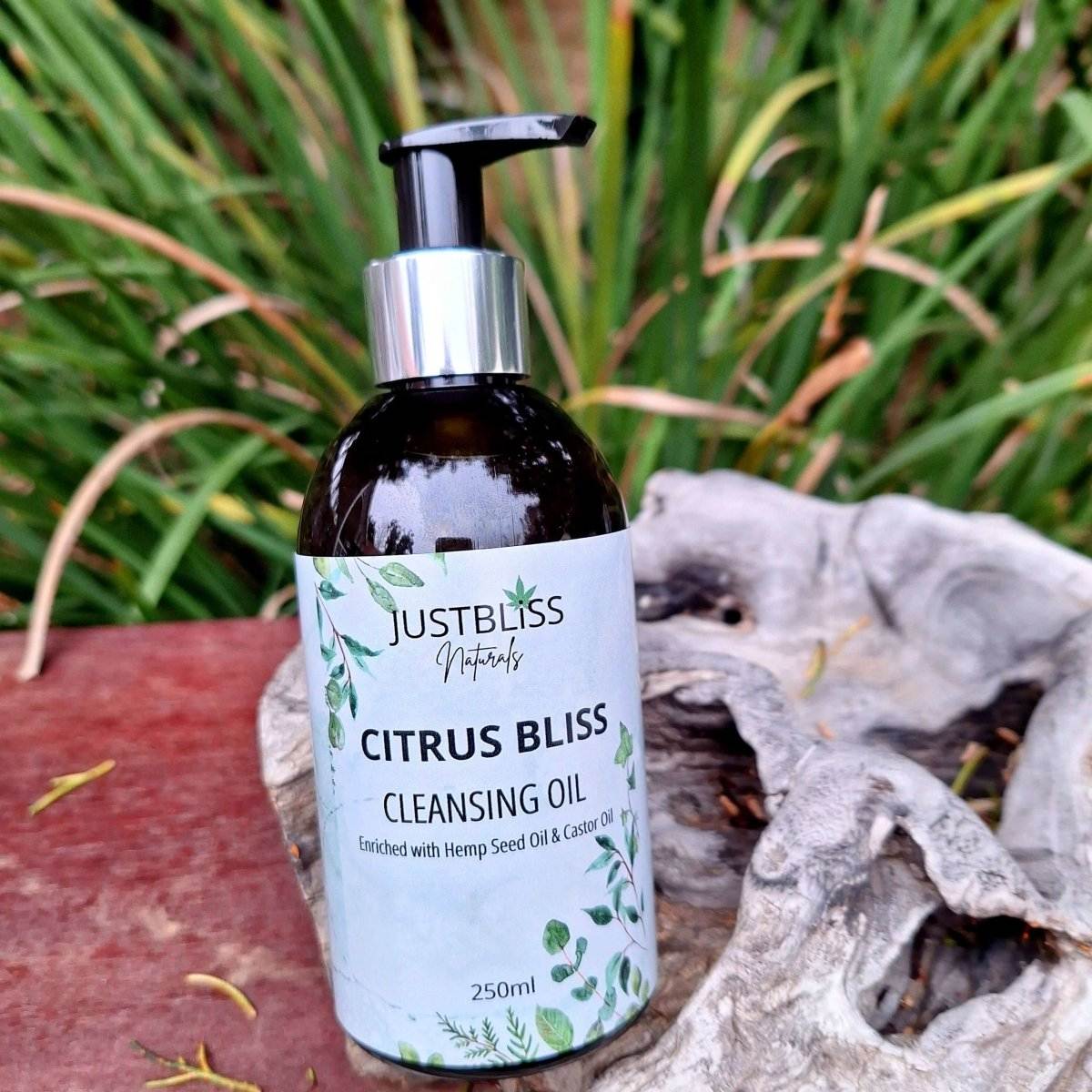 Citrus Bliss Facial Cleanser Oil bottle on a wooden surface with greenery background.