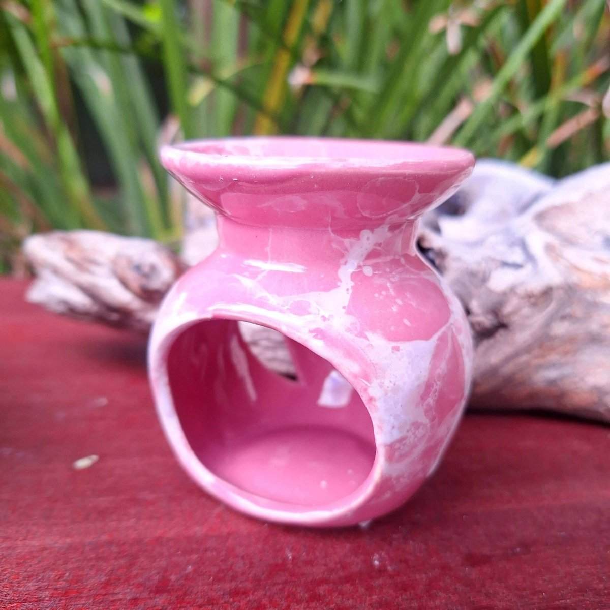 Aromatherapy Gift Box 1 pink essential oil burner on wooden surface, surrounded by greenery.