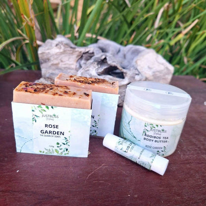 Bath, Body & Lip Set Aromatic Geranium with soap bars, rooibos tea body butter, and geranium lip balm displayed outdoors.