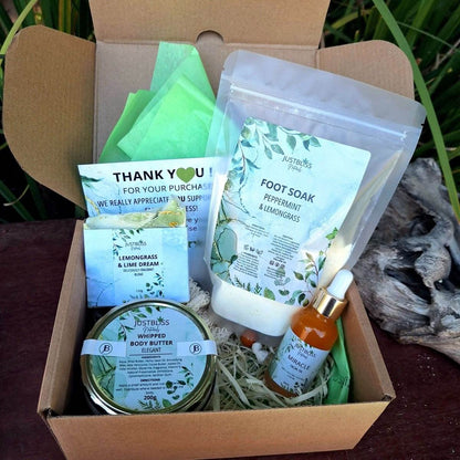 Gift box for new moms with pampering products including foot soak, whipped body butter, soap bar, loofah bag, and facial oil.