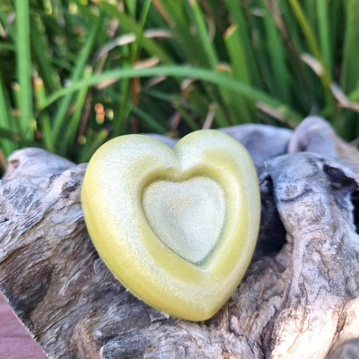 Heart-shaped lotion bar with a shimmer finish for dry skin, set on a rustic background.