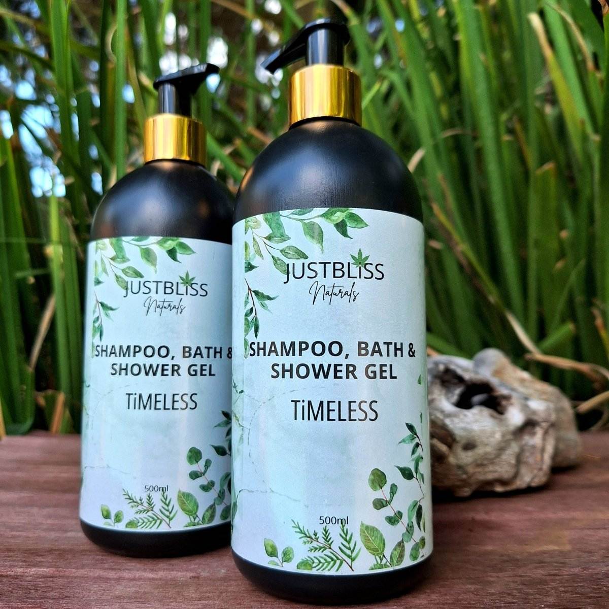 3-in1 SHAMPOO, BATH & SHOWER GEL bottles by JUSTBLiSS Naturals in a natural setting.